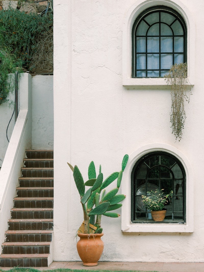 White Mediterranean house entrance with iron lanterns and a lush garden path in Coral Gables